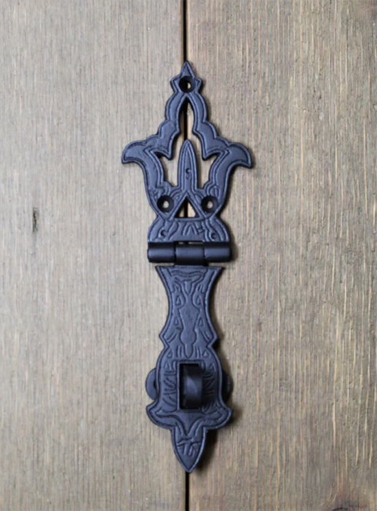 Decorative black hasp latch mounted on a wooden surface, showcasing detailed patterns and sturdy design