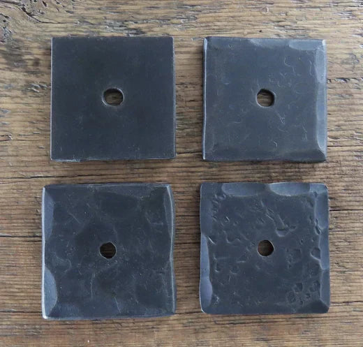 Decorative iron washers in four distinct square designs on a wooden background