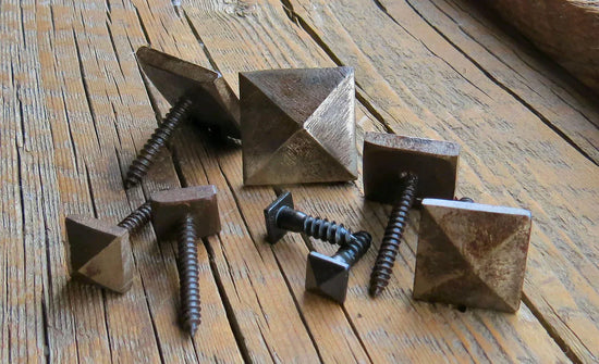 Collection of decorative screws with pyramid-shaped heads on rustic wooden surface