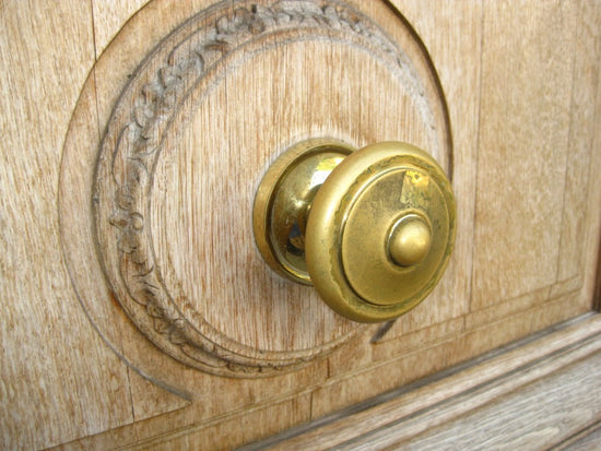 Close-up of a decorative brass cabinet knob on a wooden door panel
